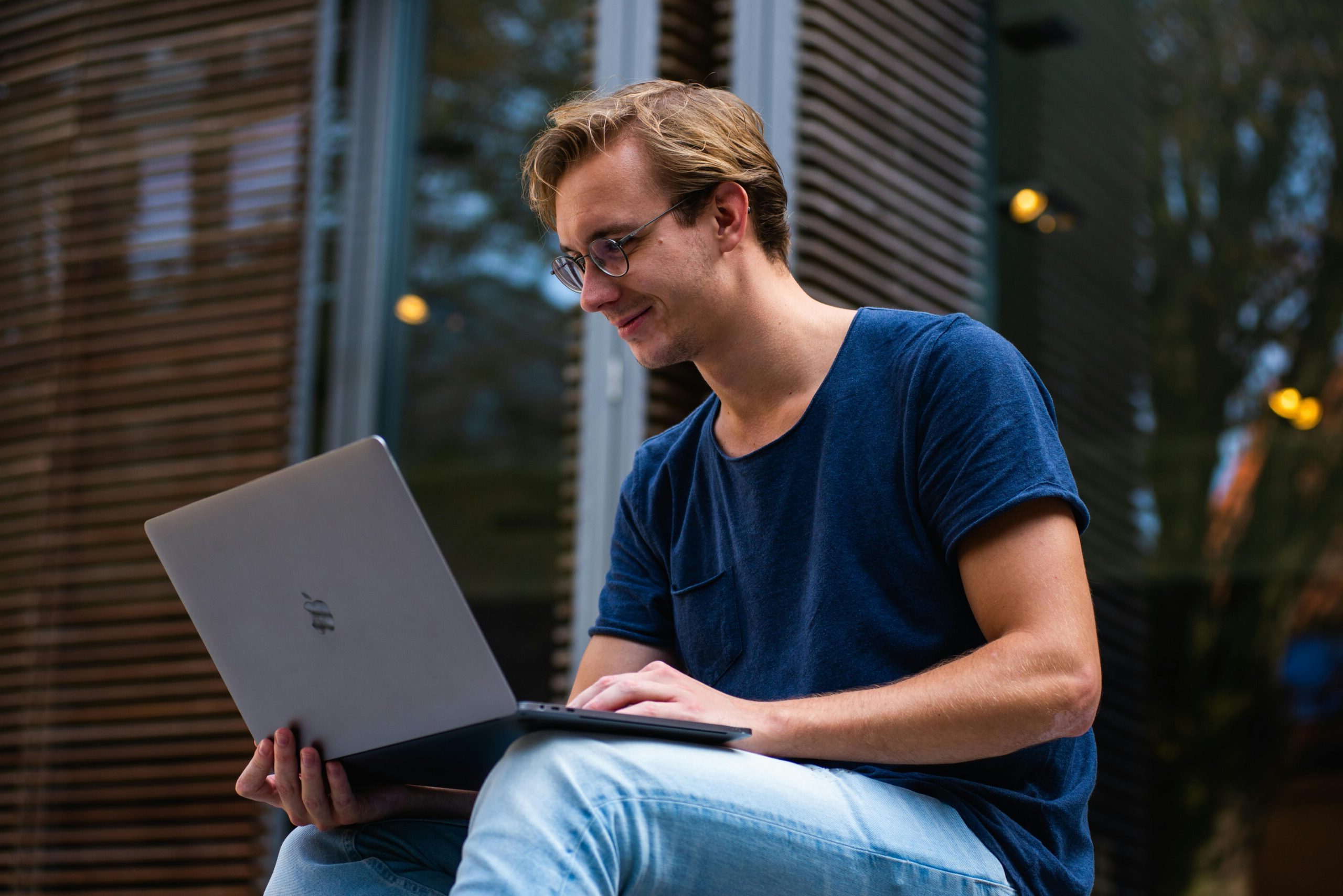 oven sonriente usando su notebook en un espacio al aire libre. Protegé tu equipo con nuestro seguro para notebooks y trabajá con tranquilidad donde quieras.